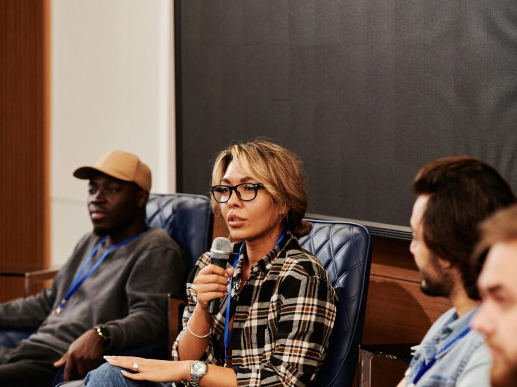 QNA SESSION A diverse group of adults engaged in a panel discussion during a business seminar. Indoors setting.